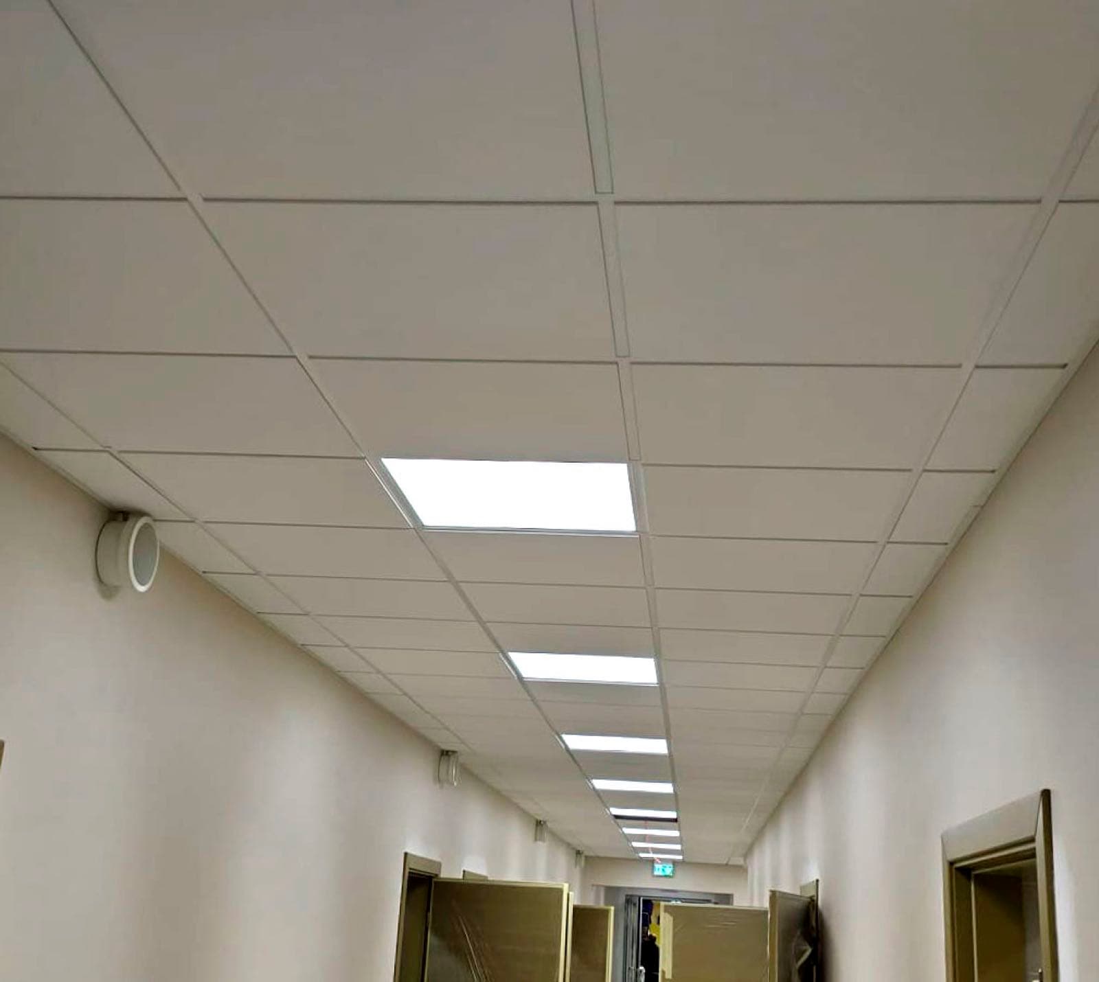 Gaišs kasešu griestu koridors ar iebūvētiem LED paneļiem birojā