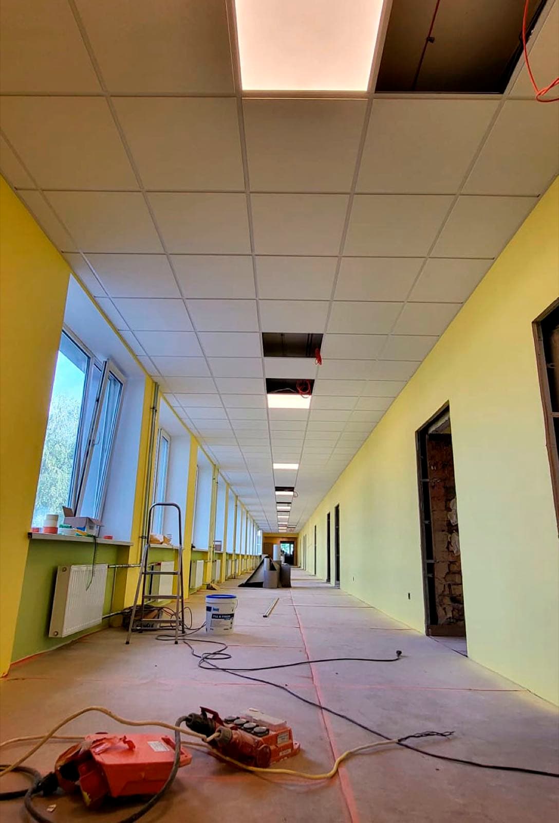 Kasešu griestu montāža skolas koridorā ar vēl atvērtām paneļu ailēm
