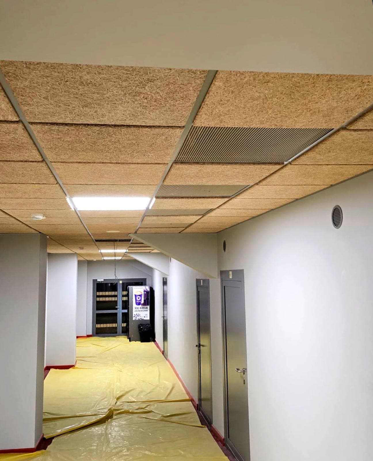 Koka skaidu akustiskie griesti koridorā pie lifta ar metāla ventilācijas režģi
